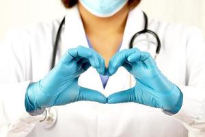 jovem médica segurando um coração vermelho em pé sobre um fundo branco foto
