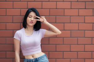 retrato de menina hipster no fundo da parede de tijolos, linda mulher asiática posar para tirar uma foto