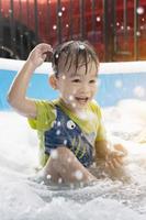 as crianças estão felizes em jogar a água no fim de semana de verão. menino asiático, família, vertical, crianças brincando com bolhas de sabão na piscina foto