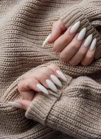 mãos de uma jovem com manicure branca nas unhas foto