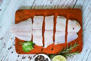 filé de peixe na placa de madeira com ingredientes aipo para cozinhar, filé de peixe pangasius cru fresco com, carne dolly peixe tilápia listrado peixe-gato foto