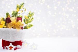 ramos de abeto, caixa de presente com lâmpadas de arco e estrela com luzes desfocadas no saco na neve. natal, ano novo. espaço de cópia foto