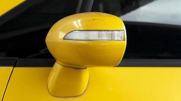 ao lado do carro close-up da asa do espelho do carro amarelo usado. condição da superfície com solavancos. foto