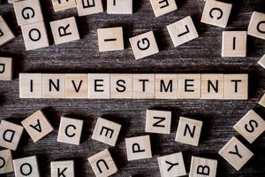 close-up de letras de madeira soletrando a palavra investimento foto