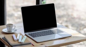 maquete de laptop em uma mesa perto de uma janela foto