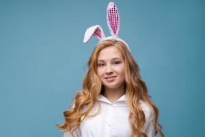 garota em orelhas de coelho rosa na cabeça sobre fundo azul do estúdio. alegre foto