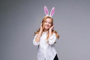 jovem mulher bonita em orelhas de coelhinho da páscoa faz um gesto normal, joga foto