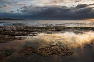 pôr do sol dramático na praia de Sydney foto