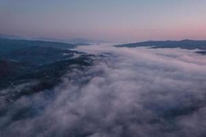 névoa da manhã e nuvens na floresta de colina foto