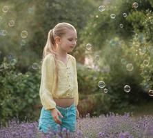 linda garotinha em um campo com lavanda. foto