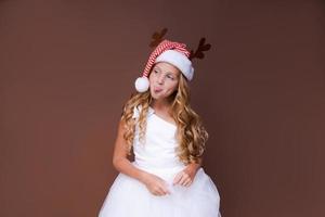 menina criança engraçada feliz na fantasia de veado de Natal vermelho sorrindo olhando para a câmera. foto