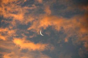 lua aparecendo atrás de nuvens laranja foto