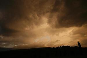 topo da colina com a silhueta do céu laranja foto