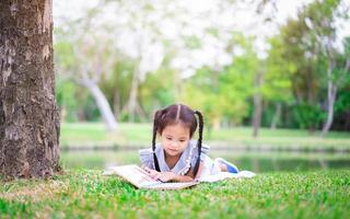 menina lendo um livro lá fora foto