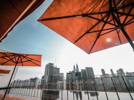 piscina na cobertura com guarda-chuvas vermelhos com vista para o horizonte da cidade foto