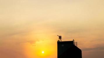 silhueta do homem no rofftop sobre fundo de luz do céu e sol, negócios, sucesso, liderança, realização e conceito de pessoas foto