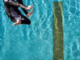 vista de alto nível uma garota pulando na piscina em um dia ensolarado foto