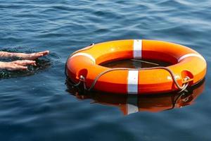 as mãos do homem alcançam a bóia salva-vidas na água. o conceito de salvar afogamento foto