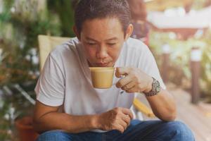 homem caucasiano em jeans e camiseta branca bebendo coffee-break no café. foto