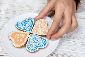 mãos seguram biscoitos em forma de coração foto