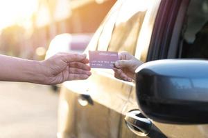 as mulheres dão cartões de crédito aos homens para pagar as compras e dirigem um carro para ela, conceito de compras drive-through foto