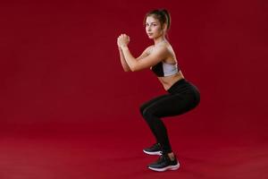 jovem está envolvida em fitness em um fundo vermelho foto