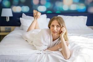 mulher está deitada em um roupão na cama, foto