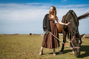 mulher jovem e bonita em um campo com cavalos. modelo de moda atraente. foto