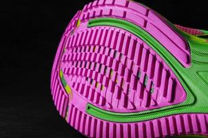sola rosa texturizada de tênis esportivos em um fundo preto. foto
