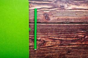 bloco de notas verde com uma caneta de feltro em uma mesa de madeira marrom, vista superior. foto