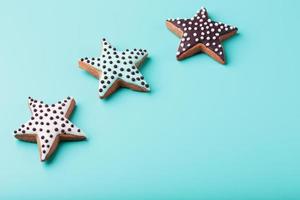 close-up de três biscoitos de gengibre vitrificados caseiros feitos sob a forma de estrelas em um fundo azul. biscoitos artesanais. espaço livre. foto