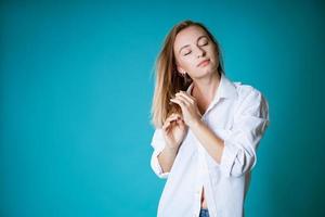 jovem posando de camisa branca e jeans em fundo azul foto