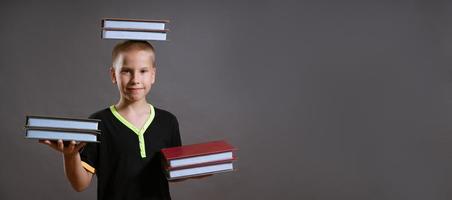 garotinho segure as pilhas de livros nas mãos e na cabeça foto