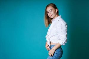 jovem posando de camisa branca e jeans em fundo azul foto