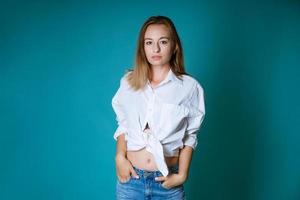 jovem posando de camisa branca e jeans em fundo azul foto