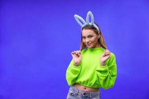 jovem em orelhas de coelho em um fundo azul foto