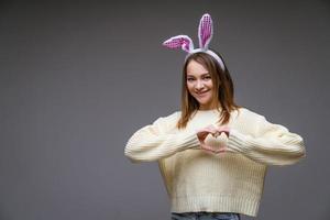 uma garota com orelhas de coelho em um fundo cinza foto