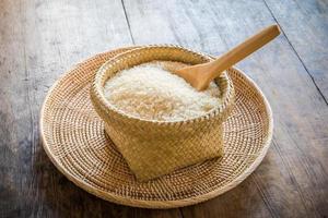 colher de pau em uma cesta de arroz jasmim na madeira foto