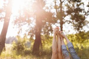 casal apaixonado deitado na grama e levantando as pernas. dia ensolarado de verão foto