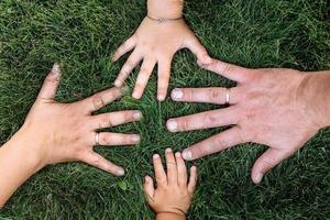 mães, pais e crianças mãos na grama verde. família feliz, conceito de infância. dia da mãe, pai, filho. família passar tempo juntos na natureza. conceito de férias de verão. foto