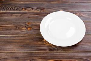 prato branco vazio na vista superior da mesa de madeira. foto