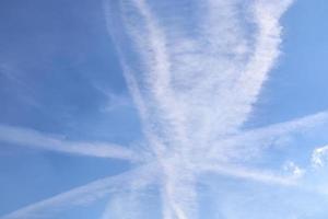 rastros de condensação de aeronaves no céu azul entre algumas nuvens foto