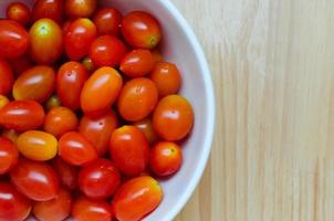 tomate cereja vermelho fresco em tigela de cerâmica branca foto