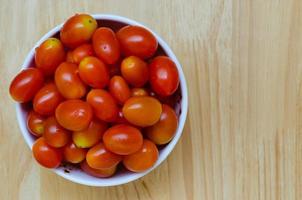 tomate cereja vermelho fresco em tigela de cerâmica branca foto