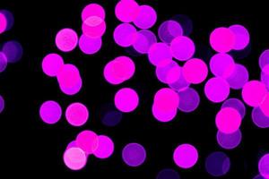 bokeh roxo abstrato sem foco em fundo preto. desfocado e desfocado muitas luzes redondas foto