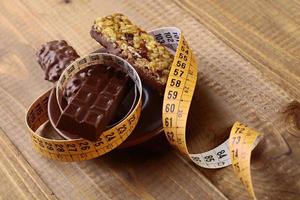 barras de chocolate apetitosas e quebradiças de amendoim com uma fita métrica foto