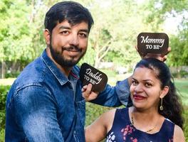 casal indiano posando para ensaio de maternidade. o casal está posando em um gramado com grama verde e a mulher está vacilando sua barriga no jardim lodhi em nova delhi, índia foto