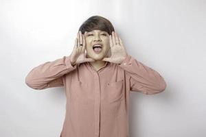 jovem mulher bonita vestindo uma camisa rosa gritando e gritando alto com a mão na boca dela. conceito de comunicação. foto