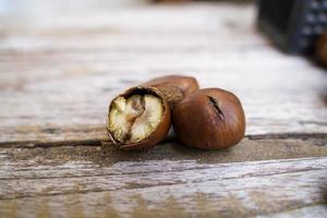 castanhas frescas isoladas em um piso de madeira, as castanhas têm um sabor doce oleoso. foto