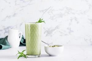 matcha latte em um copo e pó em uma tigela sobre a mesa. bebida da moda caseira foto